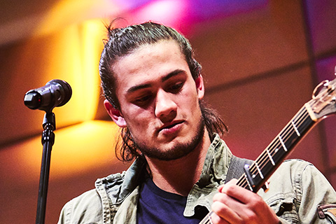 Guitarist performing live in front of a microphone